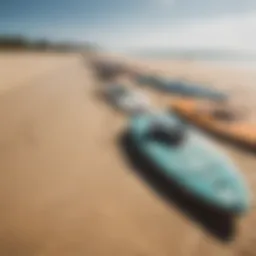 A variety of kitesurfing boards displayed on a sandy beach.